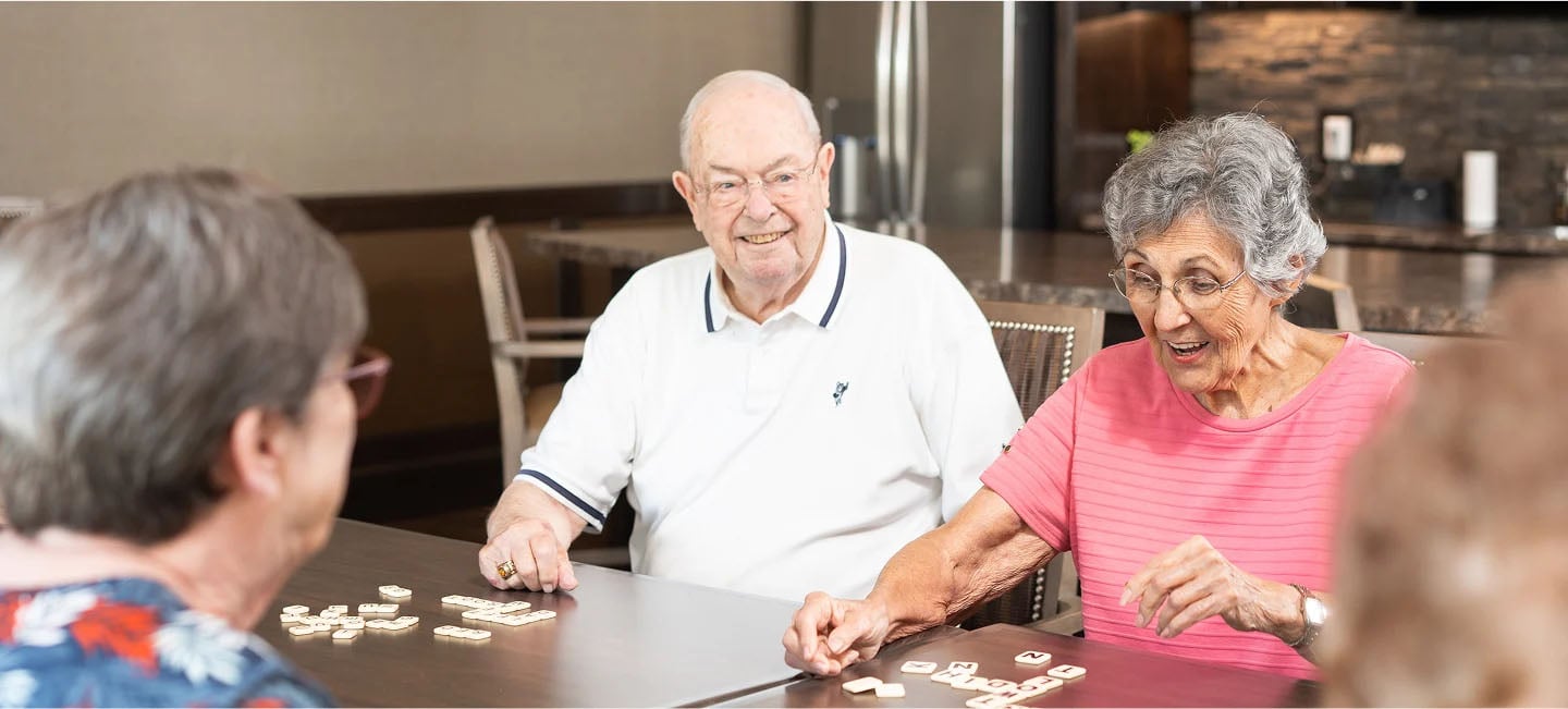 two women and man having fun playing scrabble