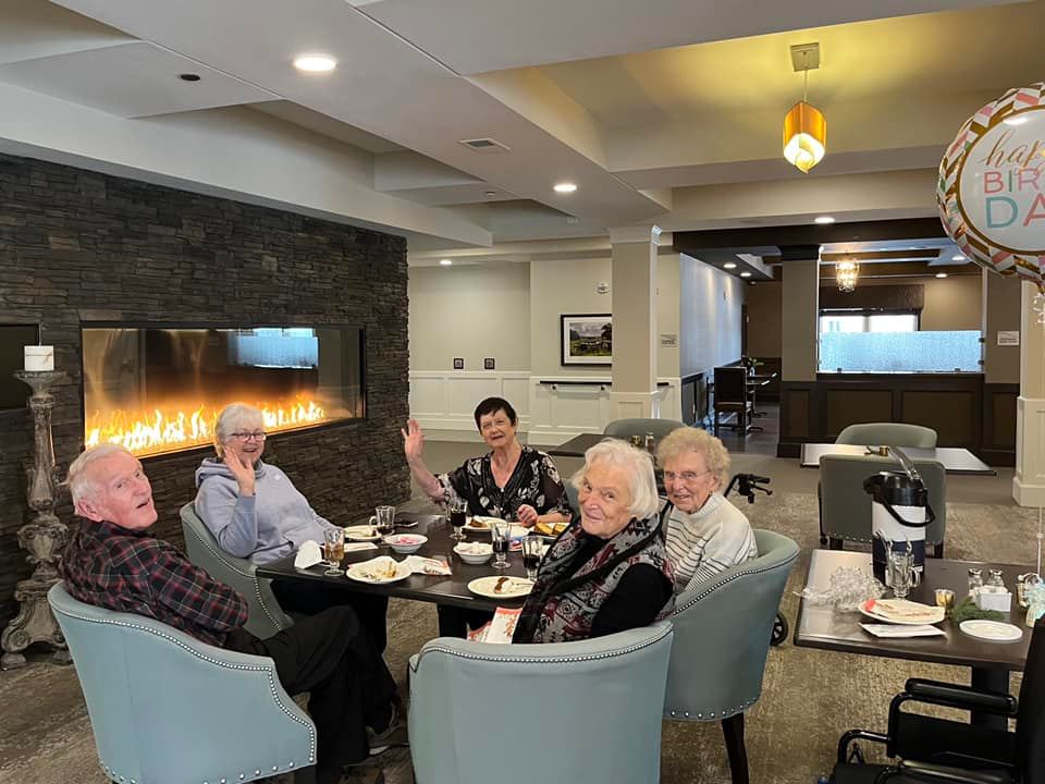 Group of Riley Crossing Senior Living residents sitting by the indoor fireplace