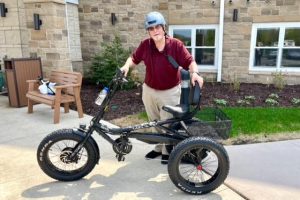 Riley Crossing senior living resident standing next to his new electric bike